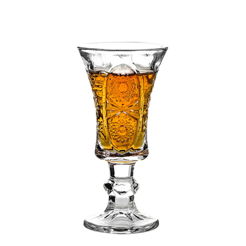 A single crystal glass filled with amber-colored liquid stands against a white background. The glass features intricate floral and geometric patterns, showcasing its elegant craftsmanship. Its sturdy base and delicate details make it a perfect choice for serving beverages with style.