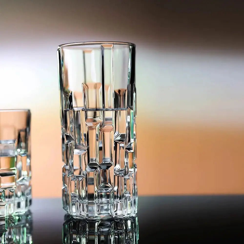 Crystal highball glass with geometric design on a reflective surface.