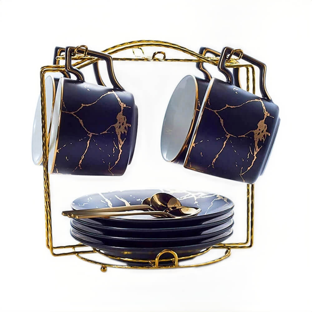 a set of four black cups with gold veining, paired with matching black saucers. The cups and saucers are displayed on a golden stand, which also holds gold-toned spoons, creating an organized and elegant presentation. The glossy black finish of the cups and saucers is highlighted by the intricate gold veining.