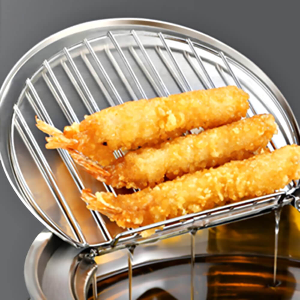 Fried shrimp draining on rack of deep fryer pot with basket, with hot oil dripping back into stainless pot after frying on stove top.