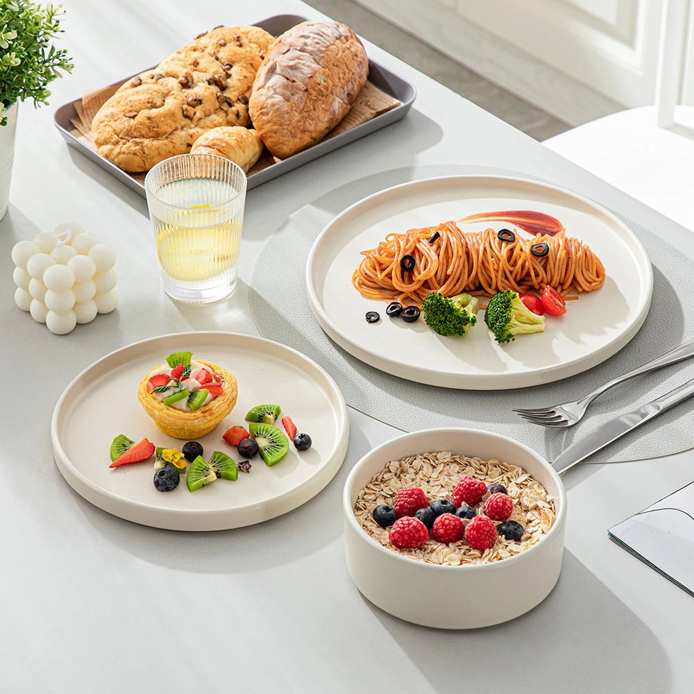 A dinner plate full of pasta, a salad plate with dessert and fruits, and a cereal bowl with oats and berries are all on a dining table from the dinnerware set stoneware collection. 