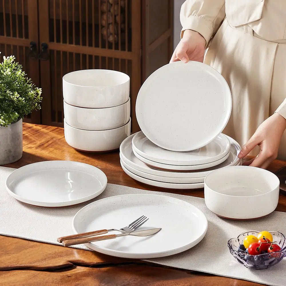 Dinnerware stoneware sets with white plates and bowls placed on a wooden dining table, person arranging the plates.