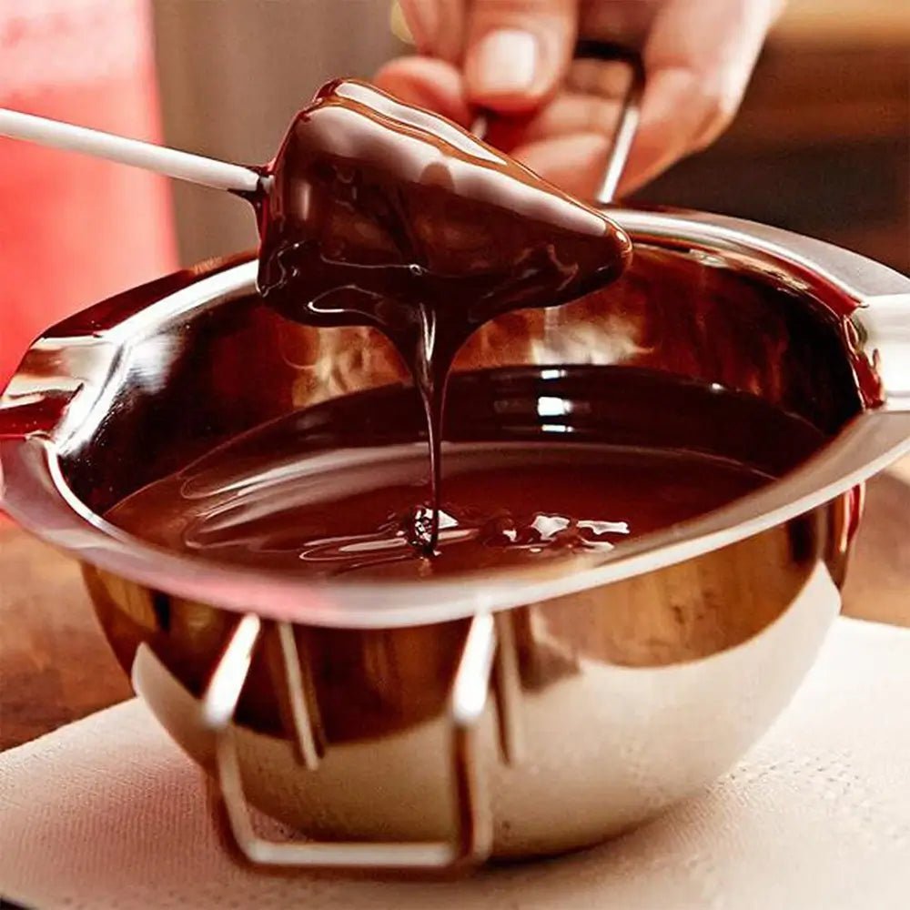 Double boiler chocolate melting in a stainless steel bowl with a spatula lifting melted chocolate.