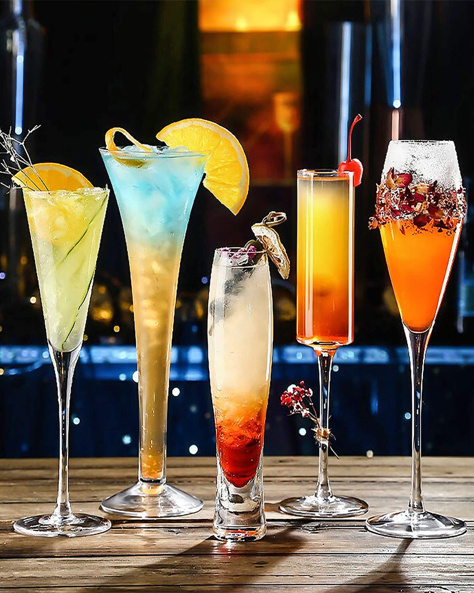 A stylish assortment of cocktails served in elegant glassware, featuring vibrant colors, fruit garnishes, and artistic presentations against a dimly lit background. Ideal for showcasing drinkware made in USA.