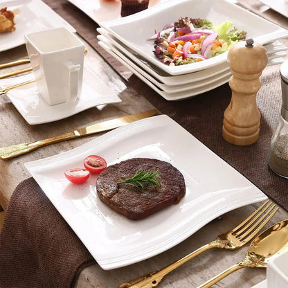 Steak with garnishes on a white plate with gold cutlery and a pepper grinder.