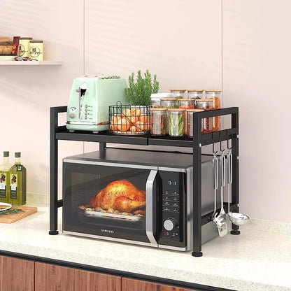 Expandable microwave stand on kitchen counter holding microwave below and toaster, jars, and cooking tools above.