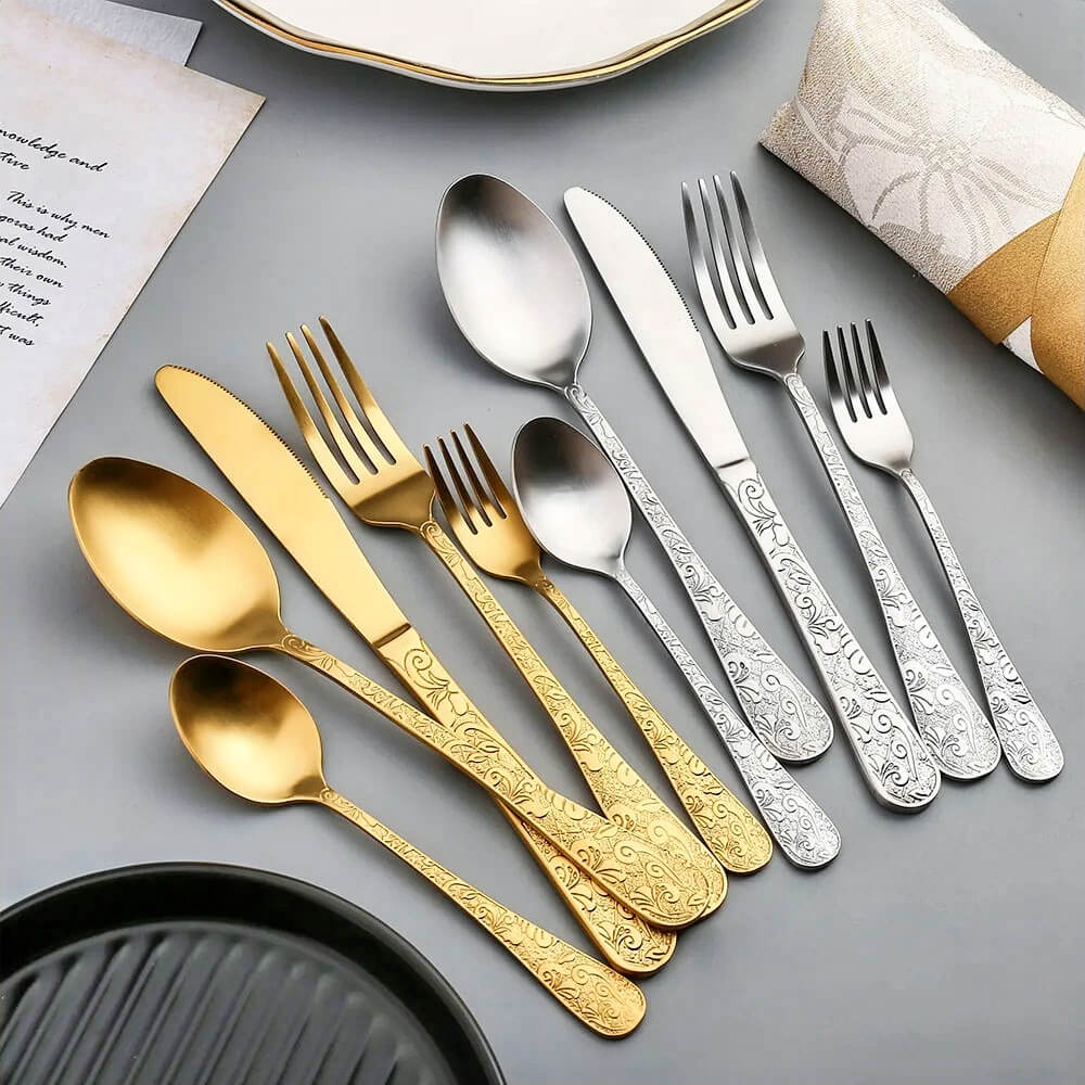 Elegant flatware gold set paired with a silver set, featuring intricate patterns on knives, forks, and spoons, ideal for sophisticated dining setups.