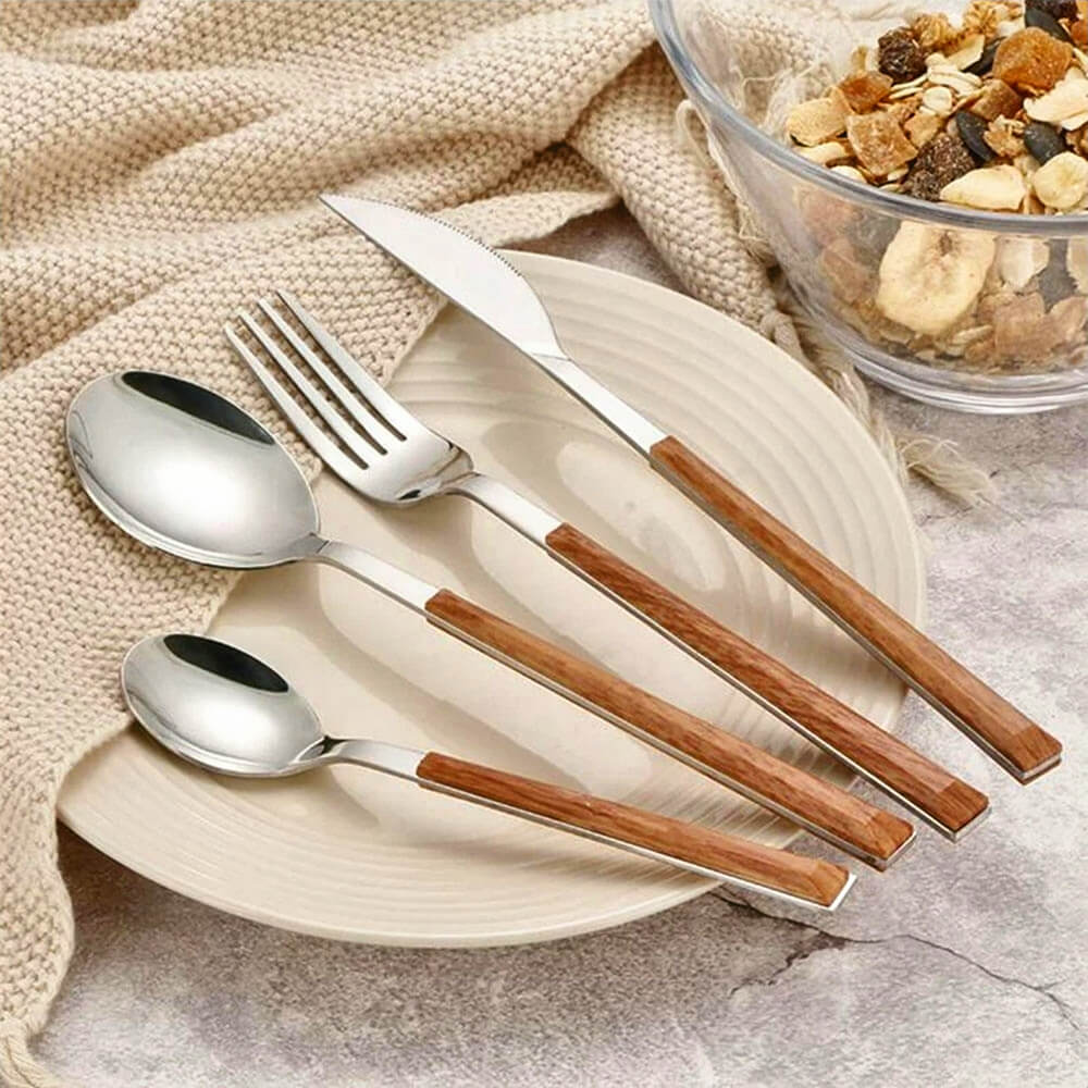 Flatware with wood handles displayed on a ceramic plate beside a bowl of dried fruit and a beige knitted cloth.