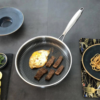 A frying pan with a honeycomb design features a stay-cool handle and a nonstick surface, with a juicy steak cooking.