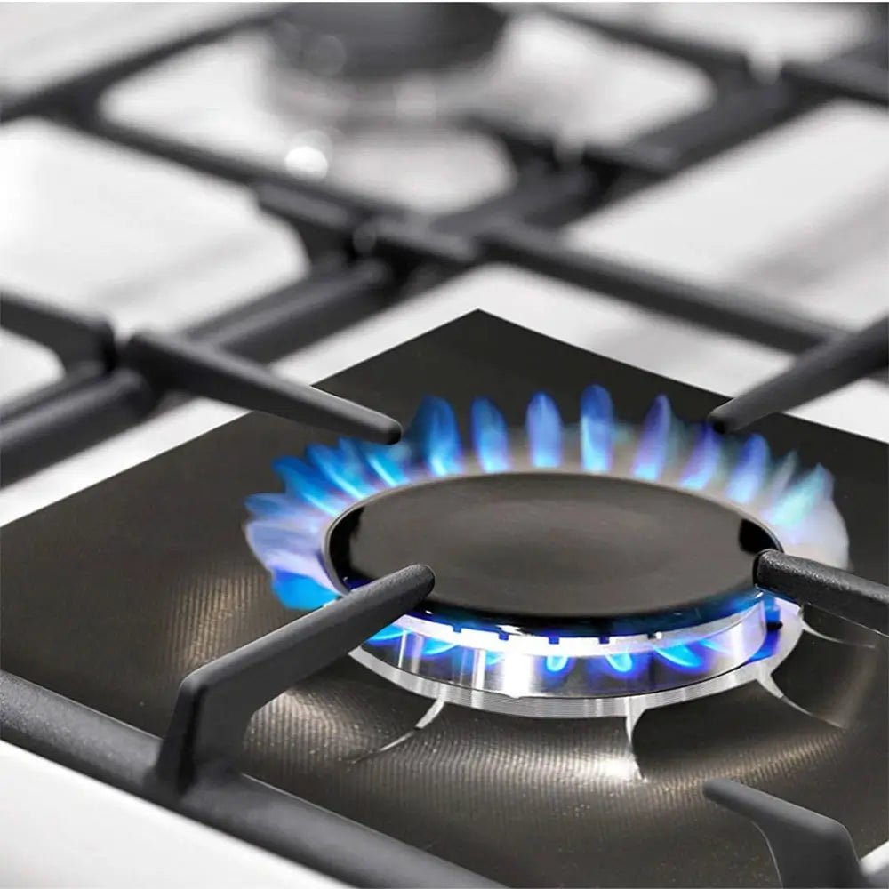 Close-up of a gas burner with blue flame on a gas range stove top burner protector reusable liner.