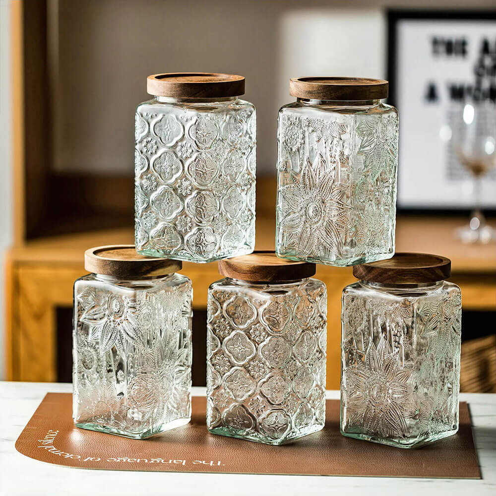 Glass canisters set with acacia wood lids, ideal for airtight and stylish kitchen storage.