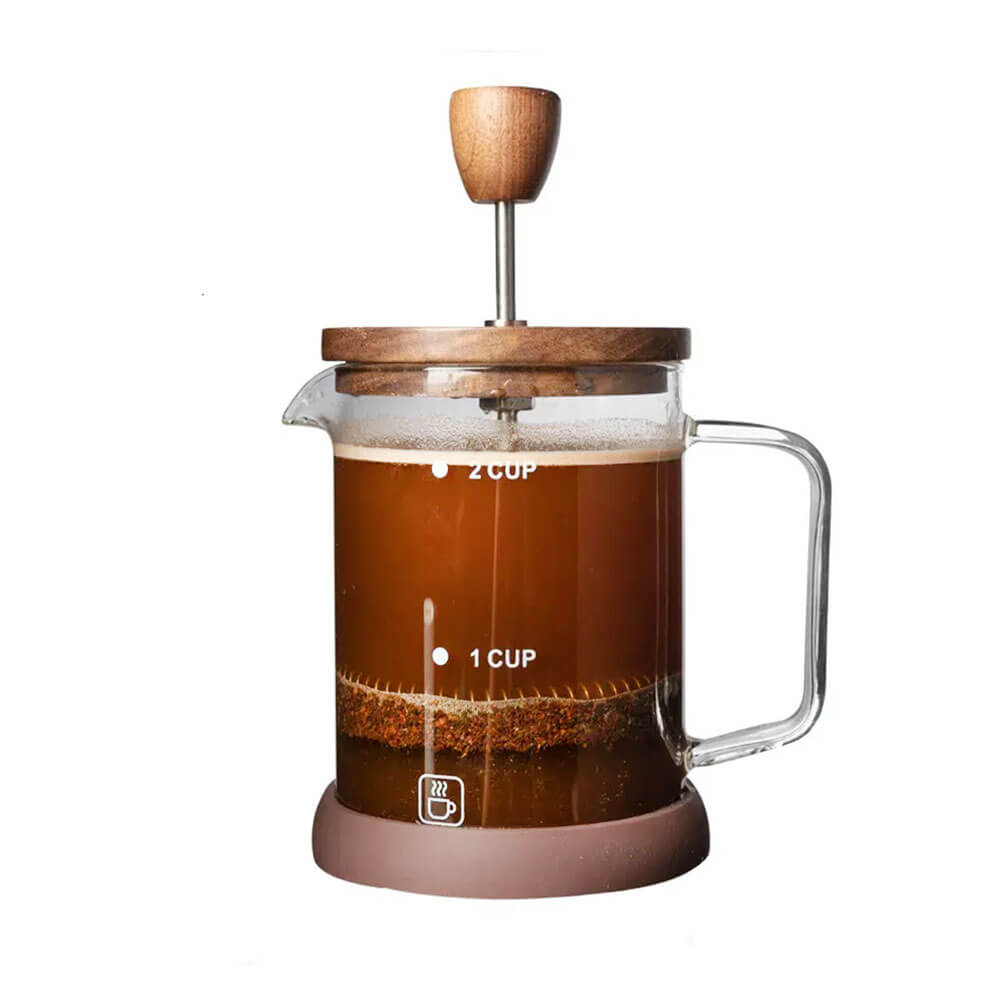 A glass French press with a clear borosilicate glass body, a natural walnut wood lid, and a stainless steel plunger. The press is filled with freshly brewed coffee, showing rich brown tones and sediment settling at the bottom. It features a sturdy glass handle and a brown silicone base for stability. The measurement markings on the side indicate a 600mL (3-cup) capacity, making it perfect for brewing smooth, barista-quality coffee.