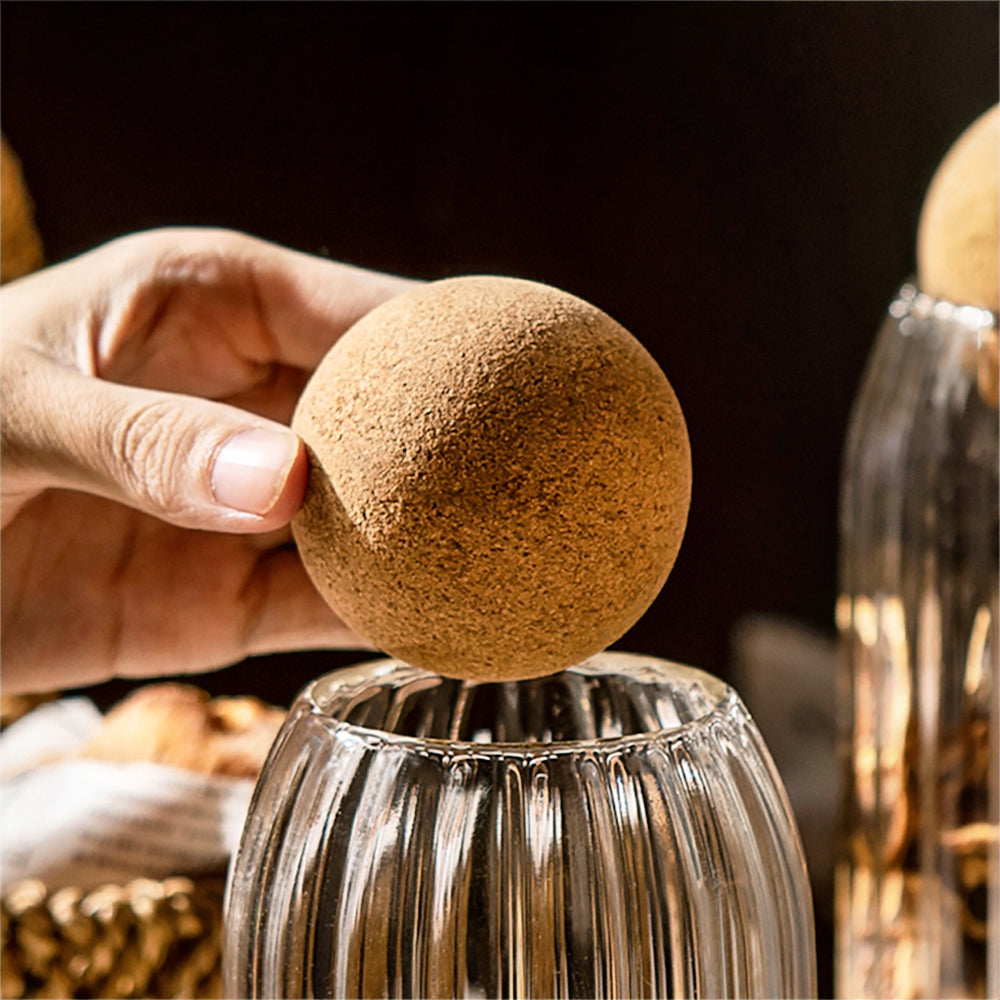 Glass jars with round cork lids, perfect for stylish kitchen storage of sugar, tea, coffee, and beans.