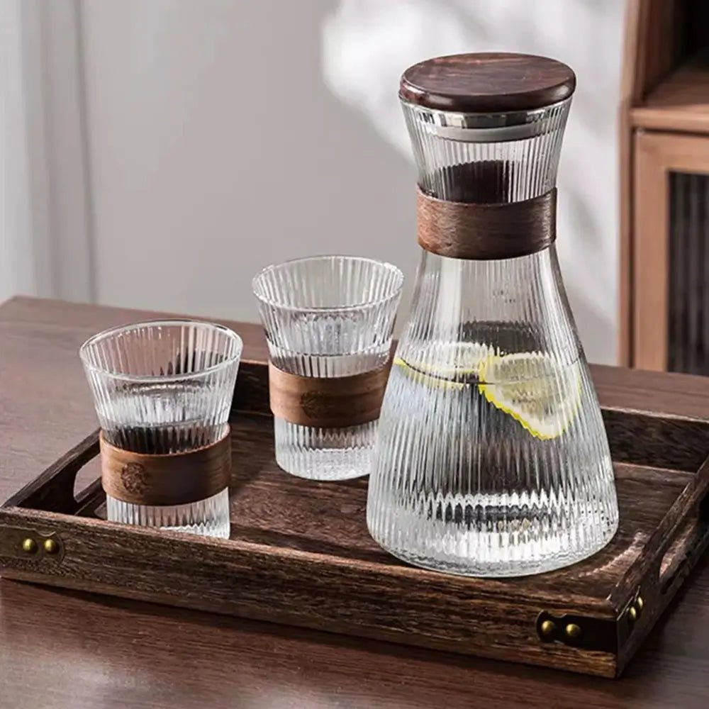 Glass pitcher set with ribbed surface, wooden lid, two ribbed glasses with wooden bands, placed on wooden tray.