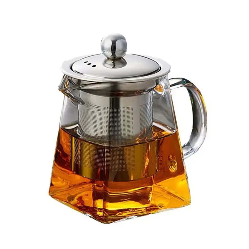 A square-shaped glass teapot filled with amber tea, featuring a stainless steel infuser and a matching metal lid with a round handle.