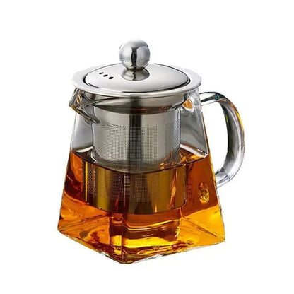 A square-shaped glass teapot filled with amber tea, featuring a stainless steel infuser and a matching metal lid with a round handle.