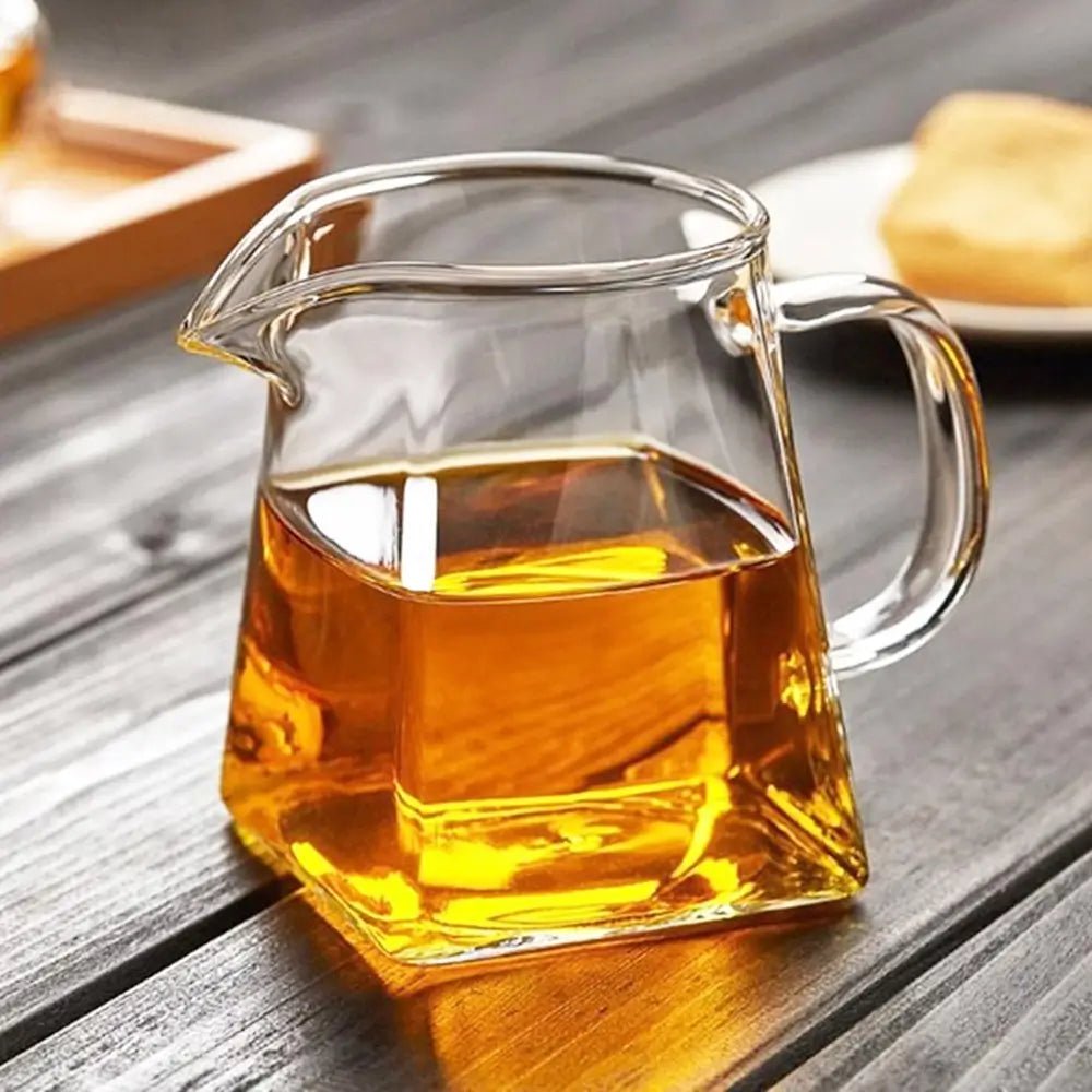 Clear glass teapot filled with amber liquid on a wooden surface.