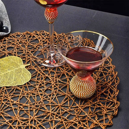 Gold rimmed glasses filled with a beverage, sitting on a stylish placemat, exuding elegance and luxury.