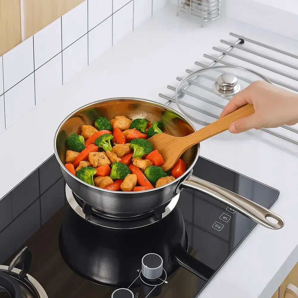 good stainless steel cookware sets frying pan on stove with broccoli, carrots, and chicken being stirred using a wooden spatula