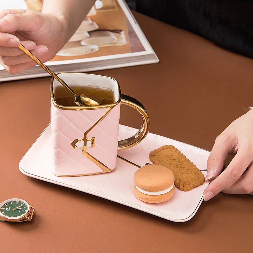 Person holding a spoon over a pink mug with gold handle on a tray with cookies and macarons.