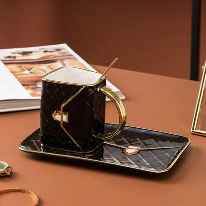 Black handbag shaped mug with gold handle on matching saucer and spoon placed on a table beside a book and watch.