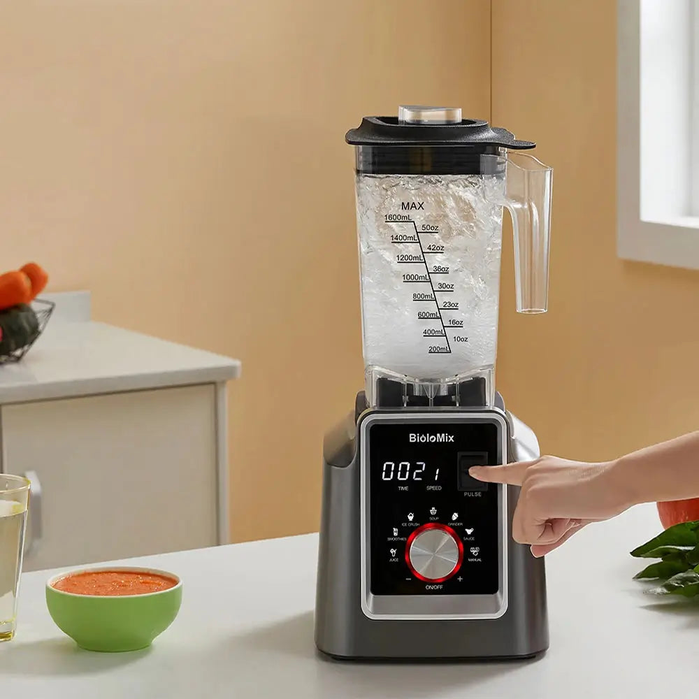 Blender on a kitchen counter with a hand pressing a button, surrounded by bowls of ingredients.