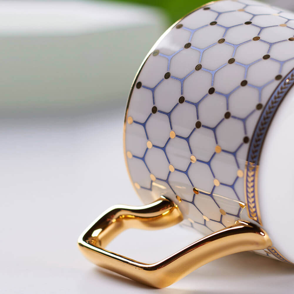 Close-up view of a luxurious honeycomb tea cup featuring a gold handle and intricate honeycomb pattern, perfect for an elegant tea experience.