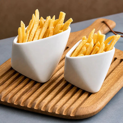 Two white ceramic bowls filled with golden french fries, placed on a wooden serving board over a gray surface.