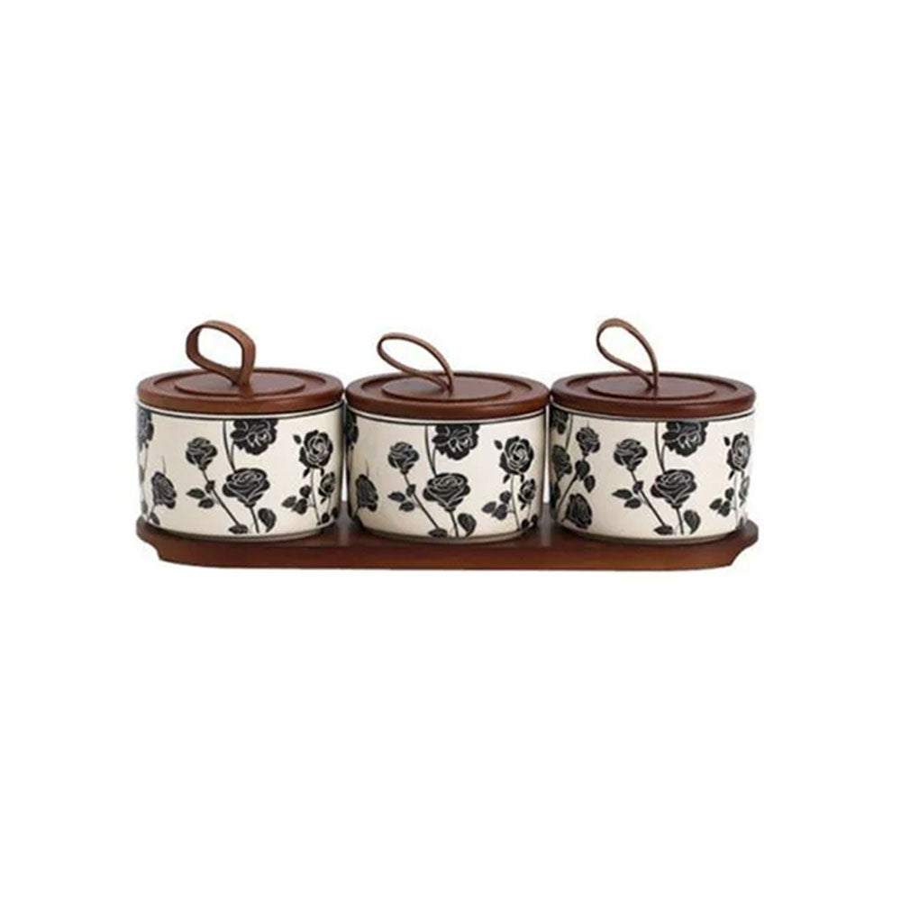 Three-piece ceramic kitchen canister set with floral design and wooden lids on a matching wooden tray.