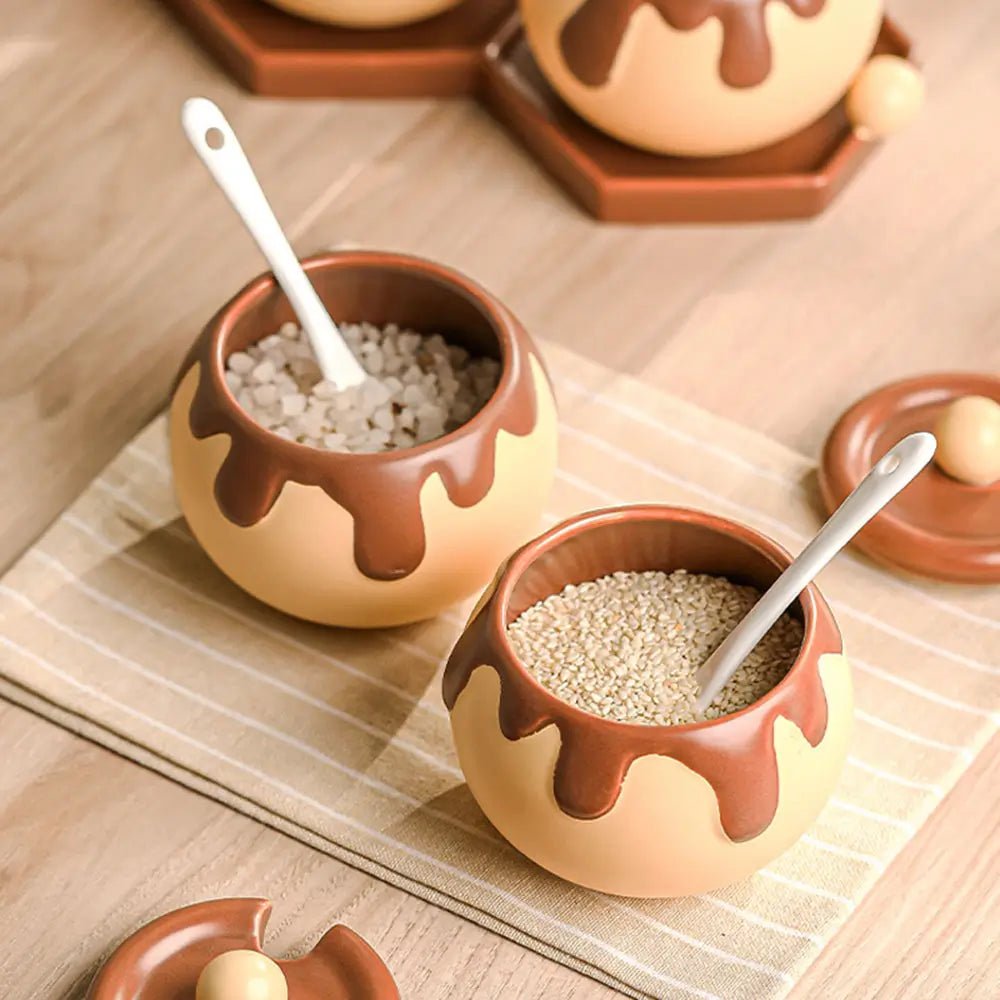 Two small ceramic containers with chocolate drizzle on a wooden surface.