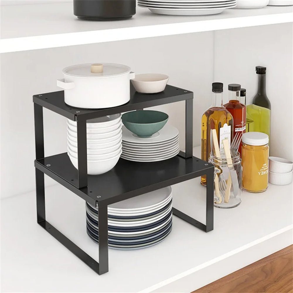 Two kitchen racks inside a cabinet holding dinner plates, salad plates, bowls, and a stockpot for organized storage.