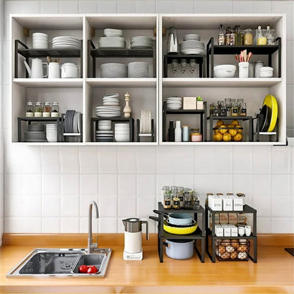 Kitchen storage racks in the cabinet and on the counter, holding dinner plates, salad plates, bowls, spice jars, utensils, and cookware items.