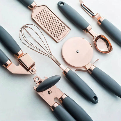 A modern kitchen tool set with rose gold finishes and dark gray ergonomic handles, including a grater, whisk, pizza cutter, garlic press, vegetable peeler, ice cream scoop, and can opener, designed for functionality and elegance in contemporary kitchens.