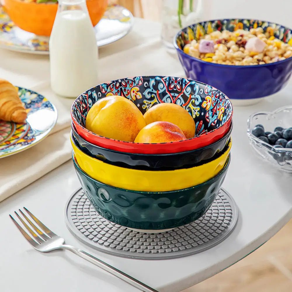 Stacked colorful ceramic large bowl for serving with peaches on a dining table.