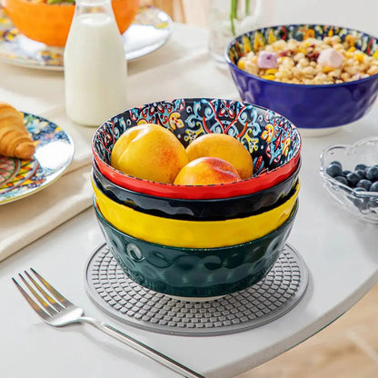Stacked colorful ceramic large bowl for serving with peaches on a dining table.