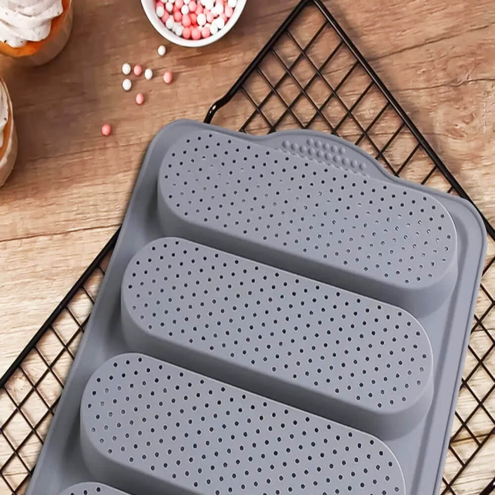 Gray silicone large loaf pan set with perforated design for even baking, displayed on wooden surface with baking accessories.
