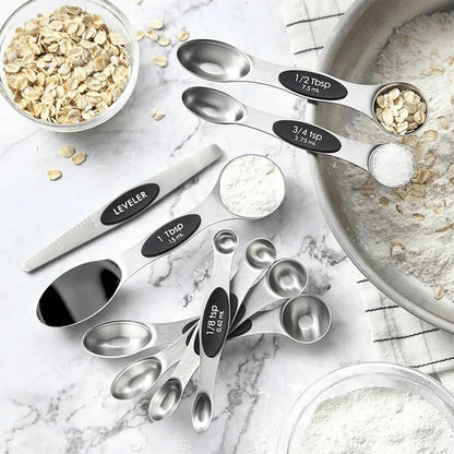 Set of stainless steel measuring spoons with black labels on a kitchen counter with ingredients.