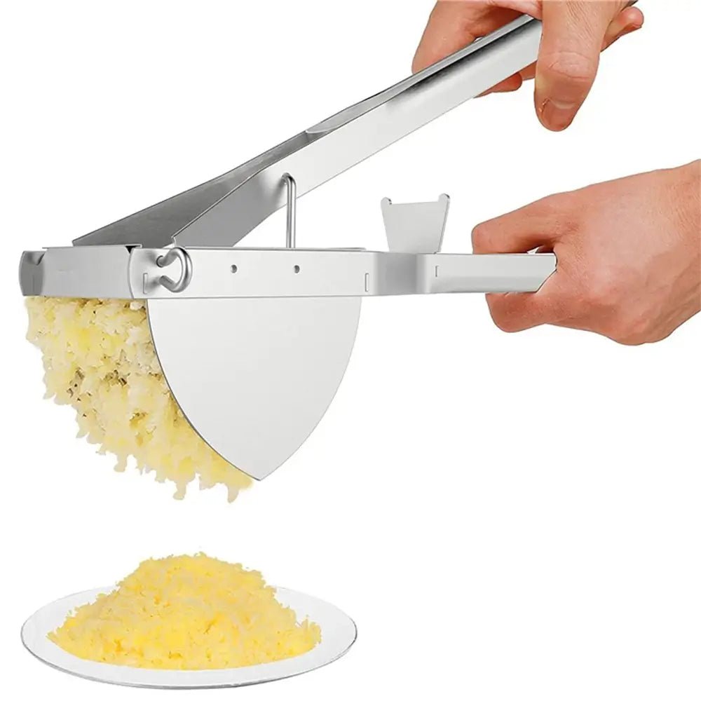 Stainless steel masha potato masher pressing cooked potatoes, smooth mash falling onto a white plate below.
