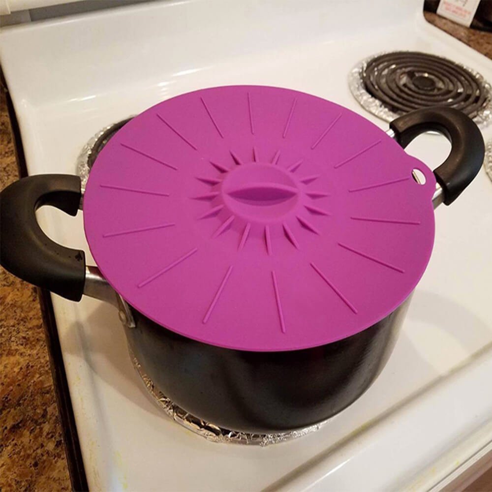 Purple microwave silicone cover placed on a pot to prevent spills and splatters during cooking.