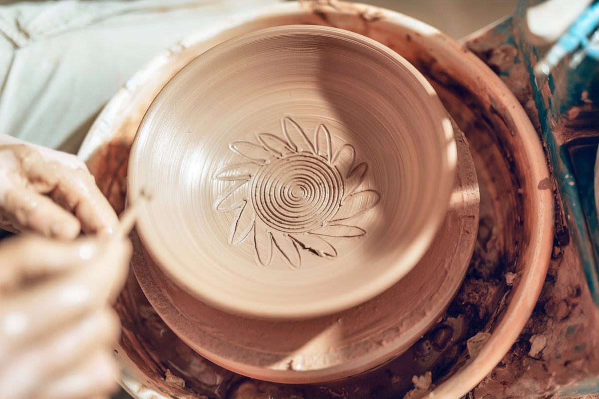 Man skillfully shaping clay on a pottery wheel, creating handcrafted bowls perfect for minimalist kitchen essentials, reflecting artisanal craftsmanship and simple elegance.