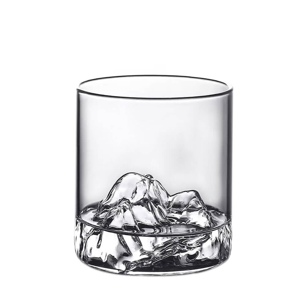 A clear glass with a sculpted mountain peak design at its base. The intricate details of the mountain shape are prominently visible through the transparent glass, creating a striking and unique visual effect. The glass is displayed against a plain white background, emphasizing its design and craftsmanship.