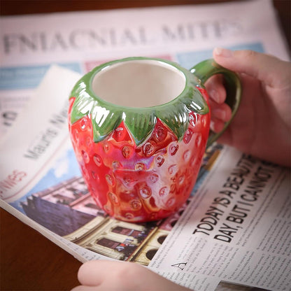 A woman holding a red strawberry-shaped mug with a detailed design and ergonomic handle.