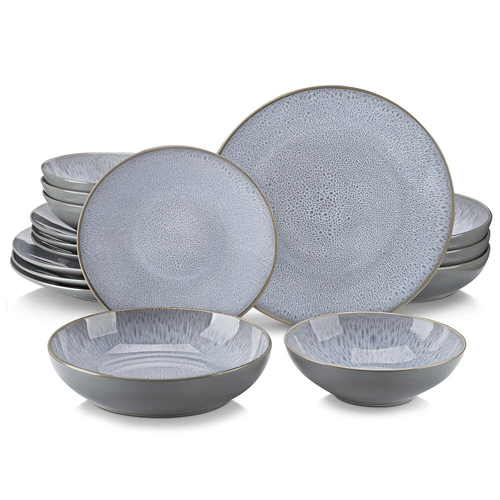 A beautifully arranged Nico stoneware reactive glaze dinnerware set featuring plates, bowls, and side plates in a textured blue-gray tone with a unique speckled reactive glaze finish, showcasing artisanal craftsmanship and modern elegance.