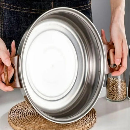 Non stick stainless steel cookware sets pot held over table mat, showing bottom design and wooden side handles.