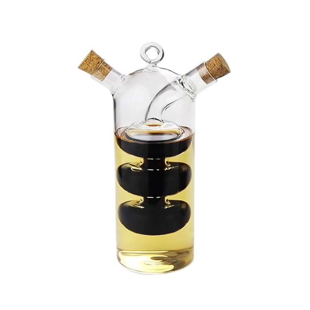 Glass oil and vinegar dual bottle with a tall, stacked design, featuring separate compartments for oil and vinegar. The bottle has two spouts with cork stoppers for controlled pouring and freshness preservation, displayed against a white background.