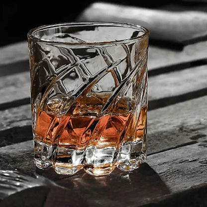 Old fashioned drinking glasses with a faceted geometric texture and amber beverage, set on a rustic wooden surface.