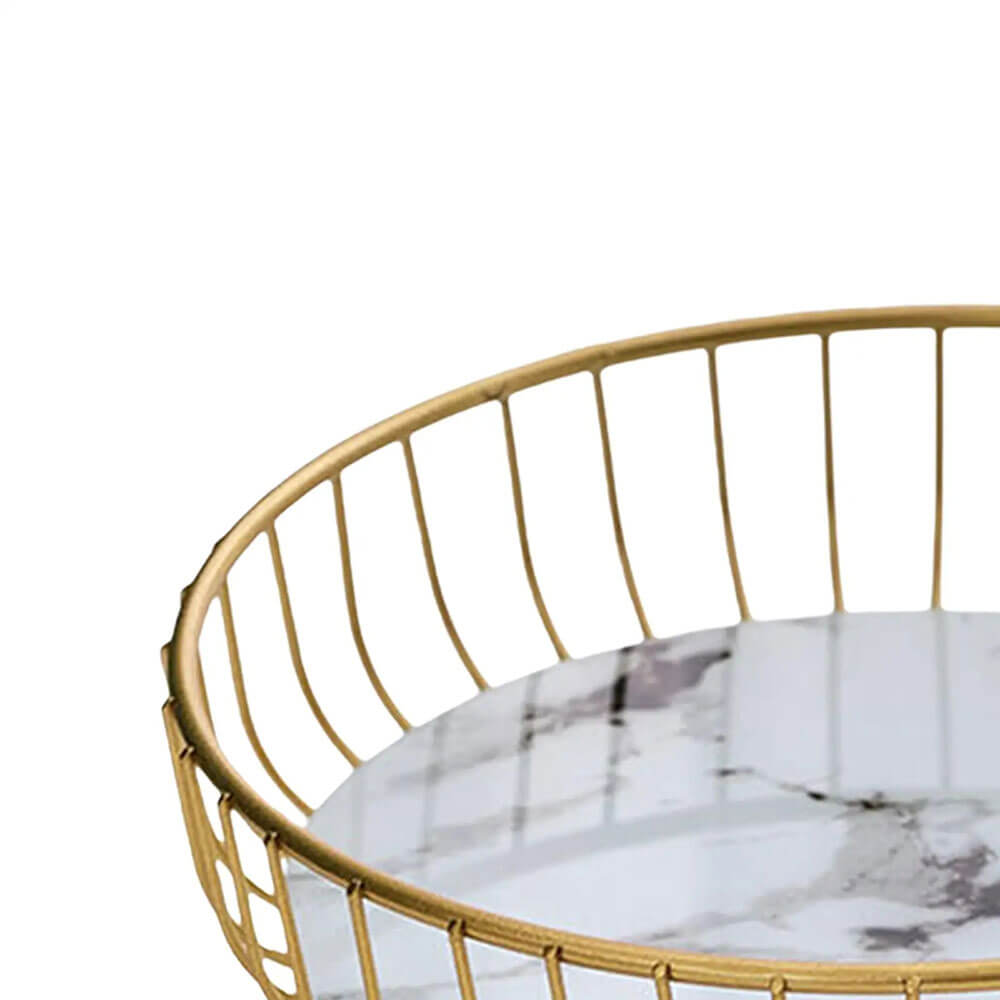 Close-up of a white marble pedestal fruit bowl featuring subtle gray veining. The bowl is surrounded by an elegant gold metal wire frame, highlighting its modern and luxurious design.