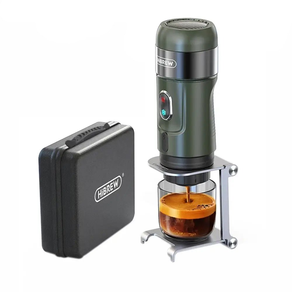 Green portable espresso maker with a glass of coffee next to a black carrying case on a white background.