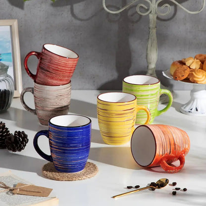 Colorful ceramic mugs on a table with a neutral background