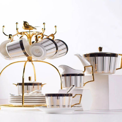 A luxurious set of tea cups and saucers featuring a white base with vertical black and gold stripes, complemented by gold-plated handles. The set includes a teapot, creamer, and a gold stand for hanging the cups, showcasing a cohesive and elegant design perfect for tea-time gatherings.